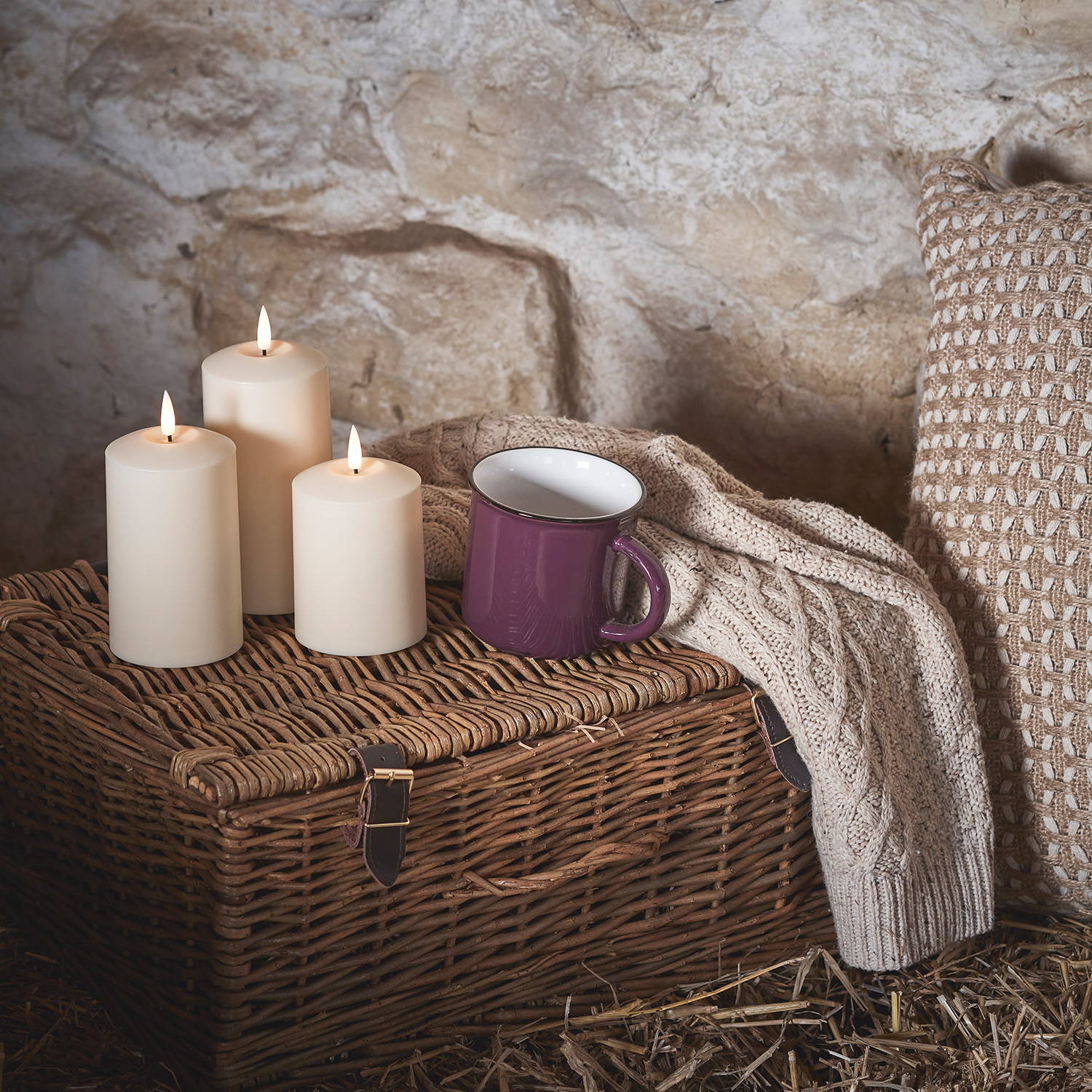 3 LED ivory pillar candles on a wicker basket with an autumn mug and cosy jumper.