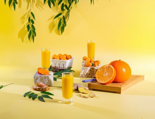 Bright yellow backdrop featuring orange juice, fruit, and vibrant garnishes.