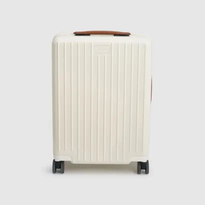 White suitcase with a textured surface and brown handle on a gray background.