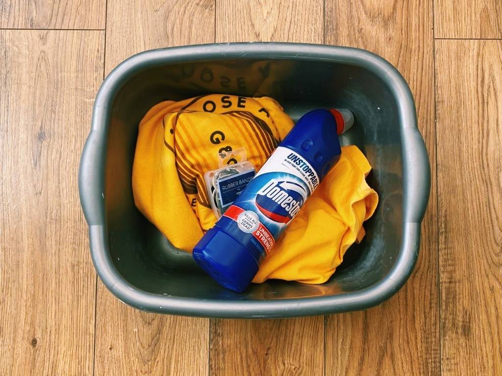 Bleach, rubber bands and t-shirt in washing bowl