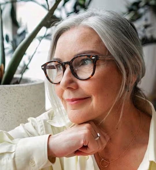 Woman with grey hair wearing Fierce Black, thick black round glasses