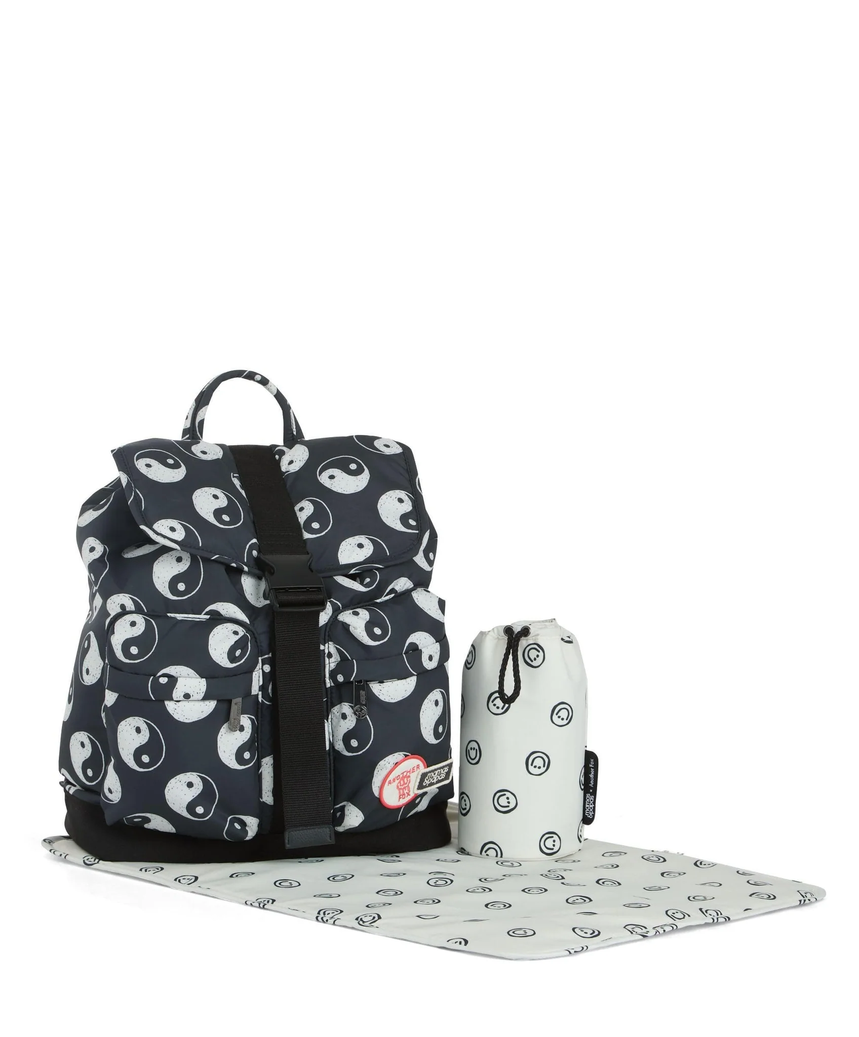 Backpack with yin-yang pattern and matching accessory pouch on a mat.