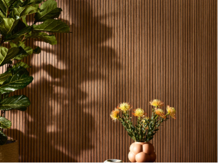DJH Walnut on a wall with a potted plant and a vase with yellow flowers in front.