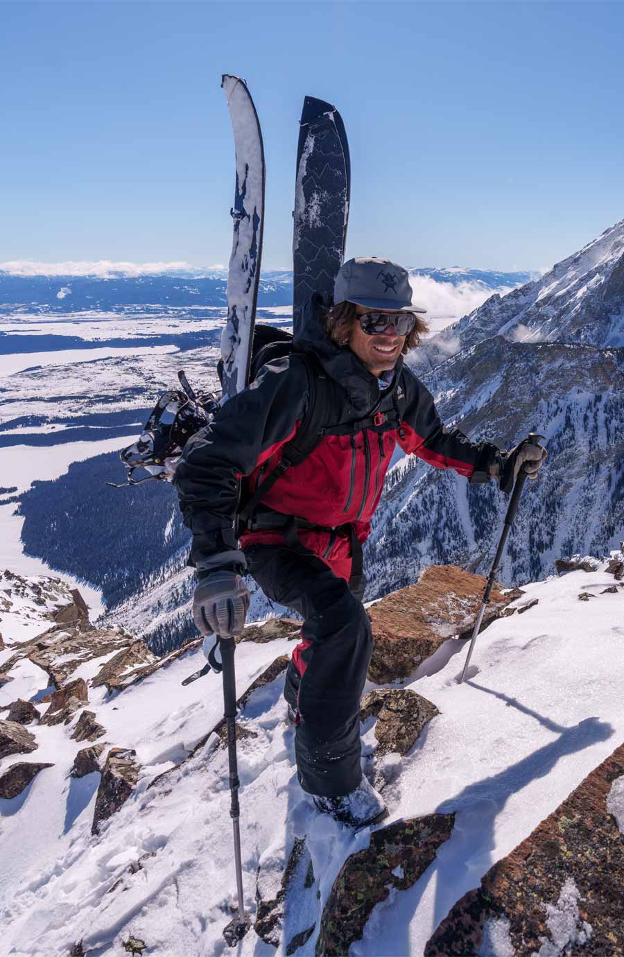 Splitboarder climbing a snowy mountain with ski equipment and poles.