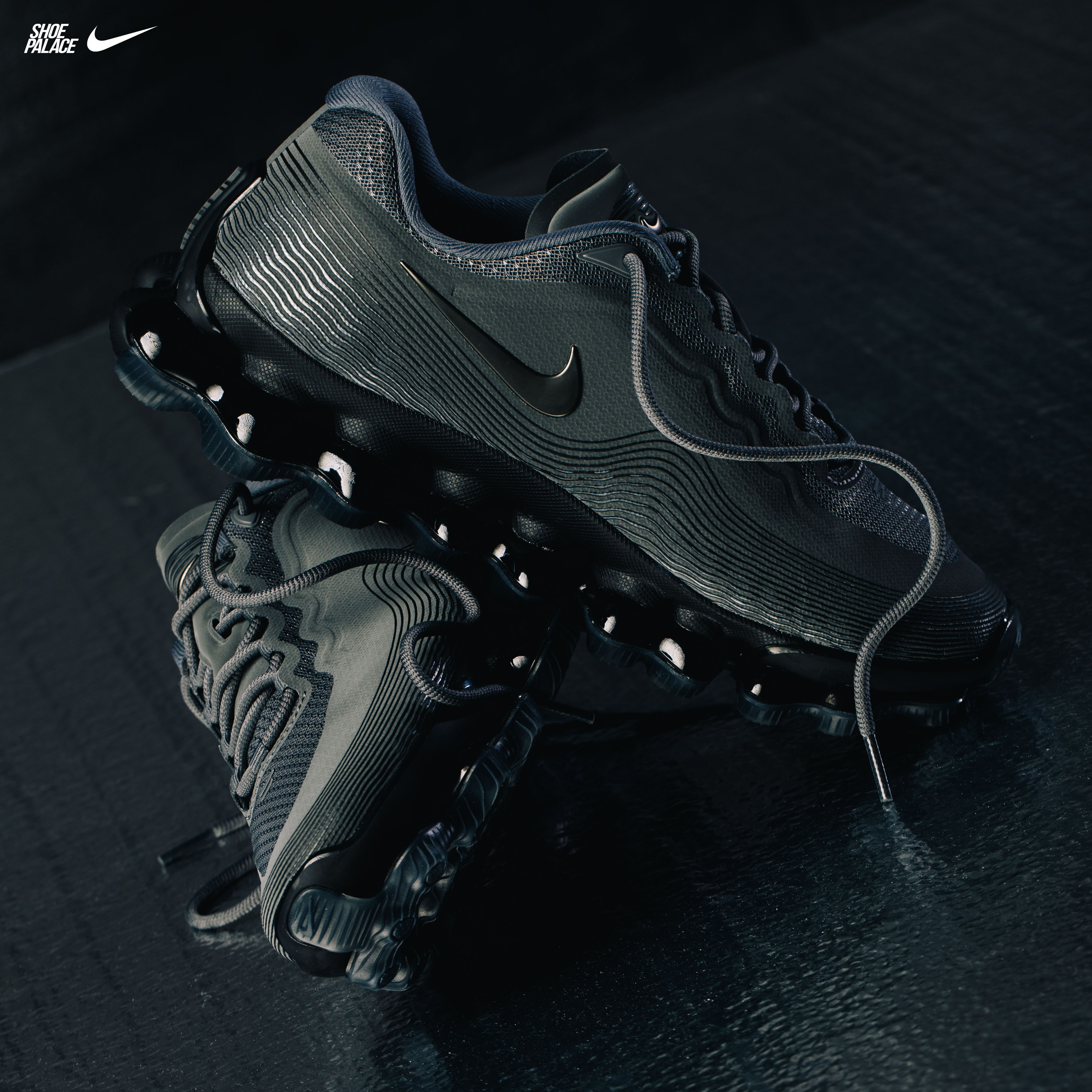 A pair of black Nike shoes on a dark surface.