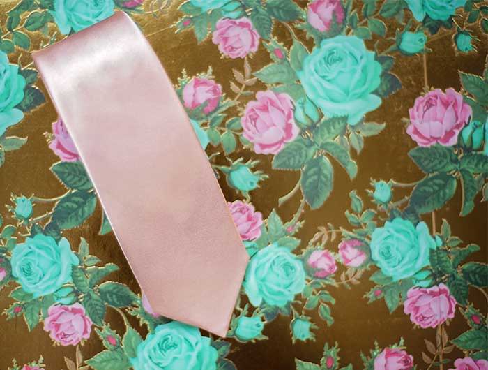 Blush pink solid wedding tie on a floral backdrop