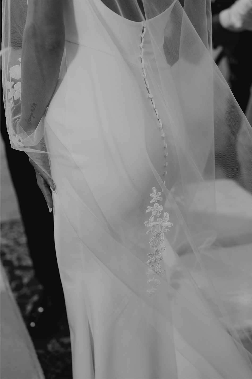 Bride's back with intricate dress detailing and flowing veil.