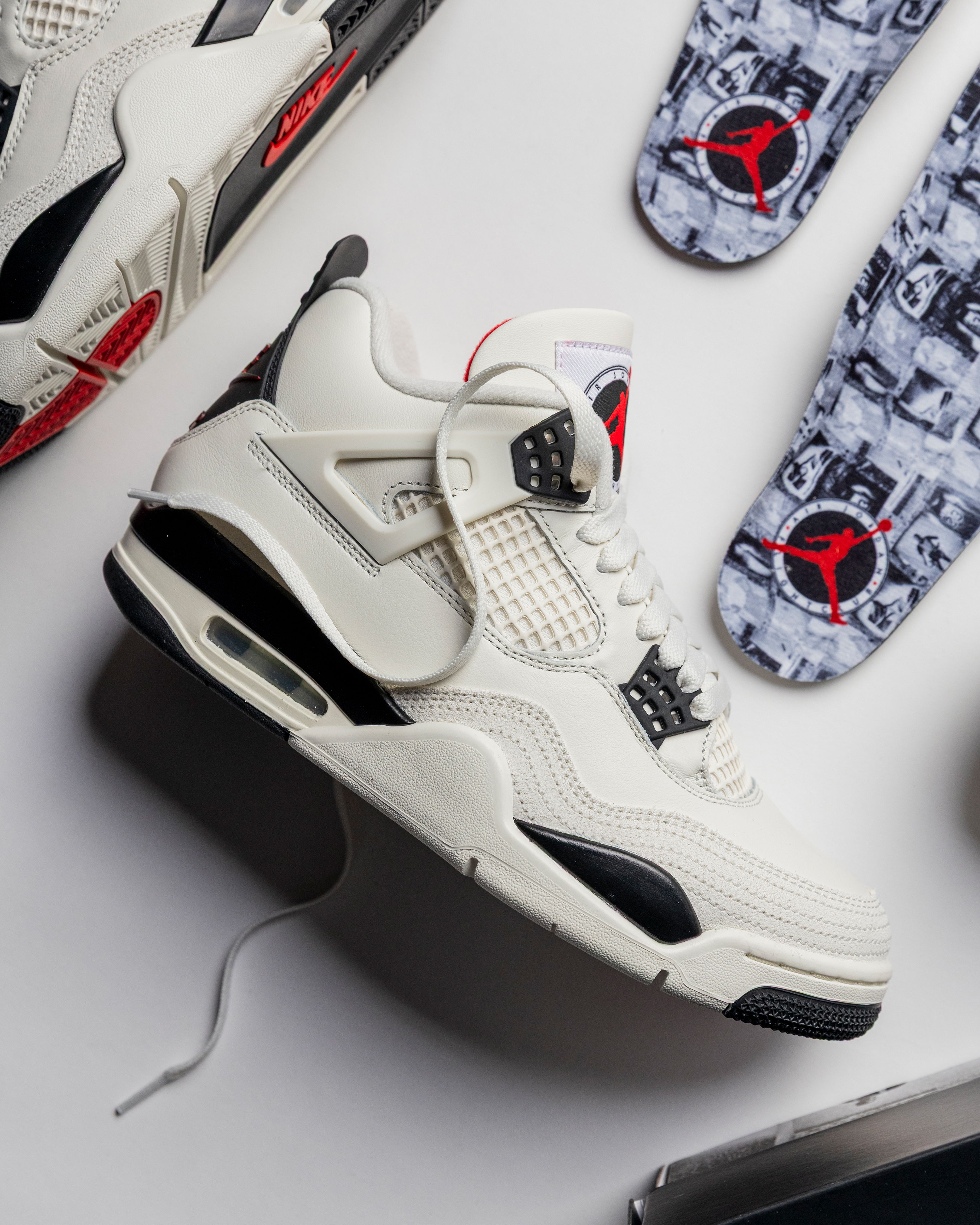 White and black Air Jordan 4 sneakers with patterned insoles.