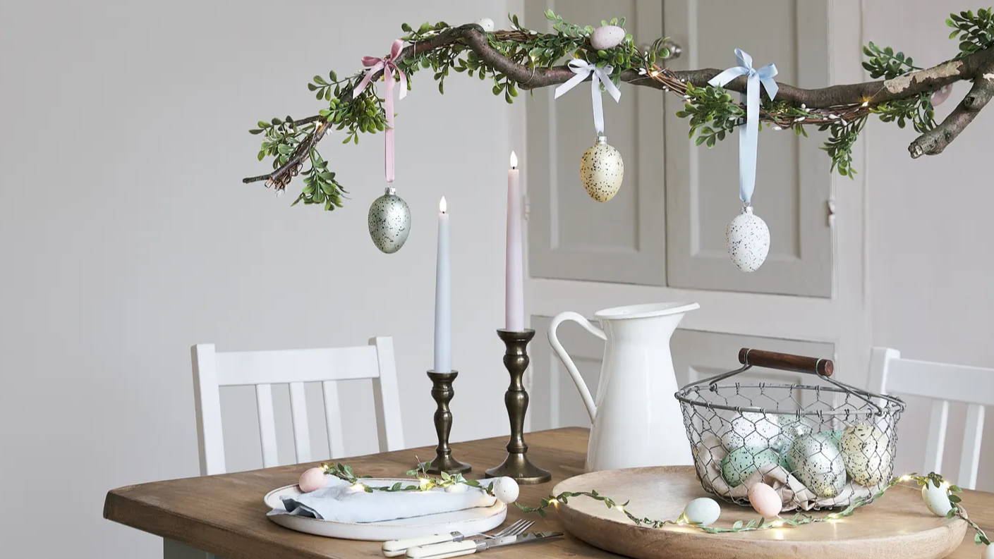 Completed hanging branch Easter table decorationand garland hanging above a dining setup