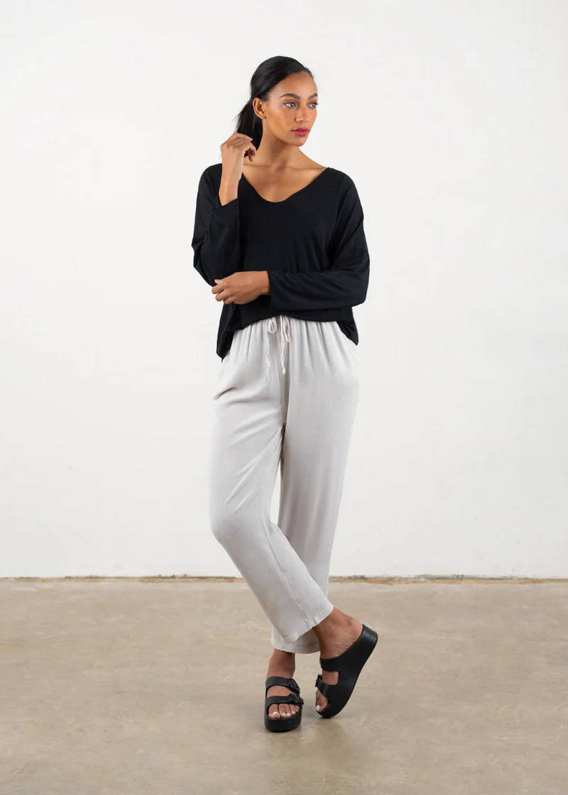 A model weaing a black long sleeved top with off white floaty crepe trosuers and black platform buckle slides