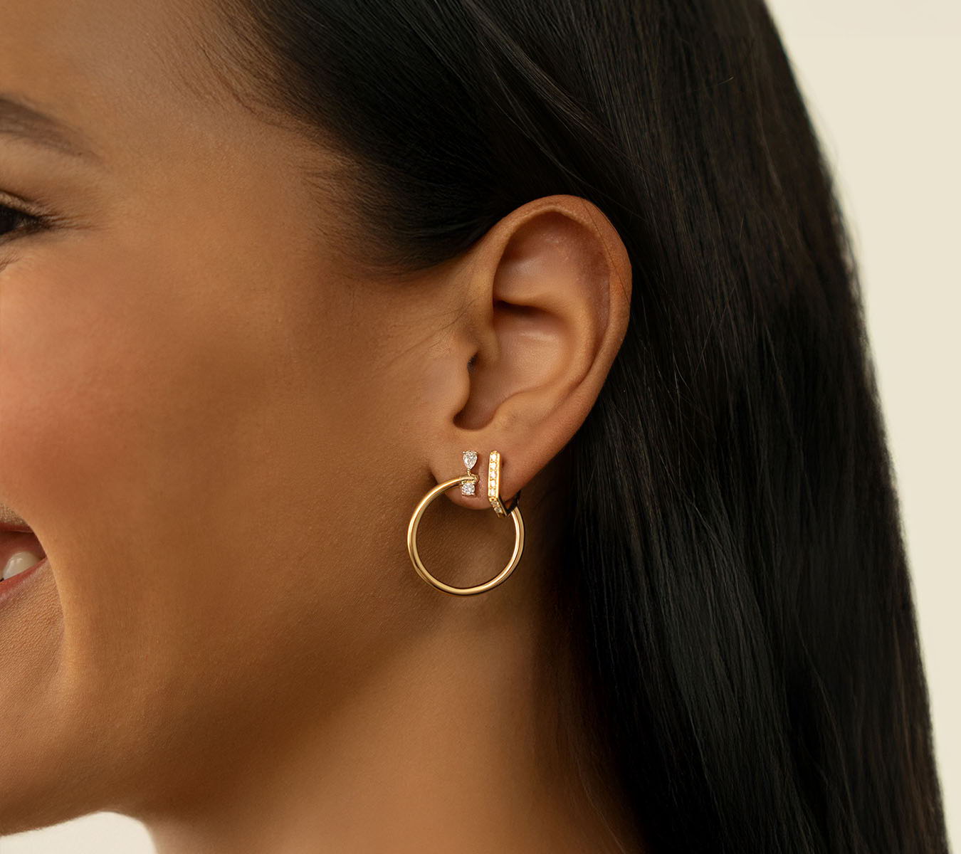 Woman smiling, wearing hoop earrings with long dark hair.