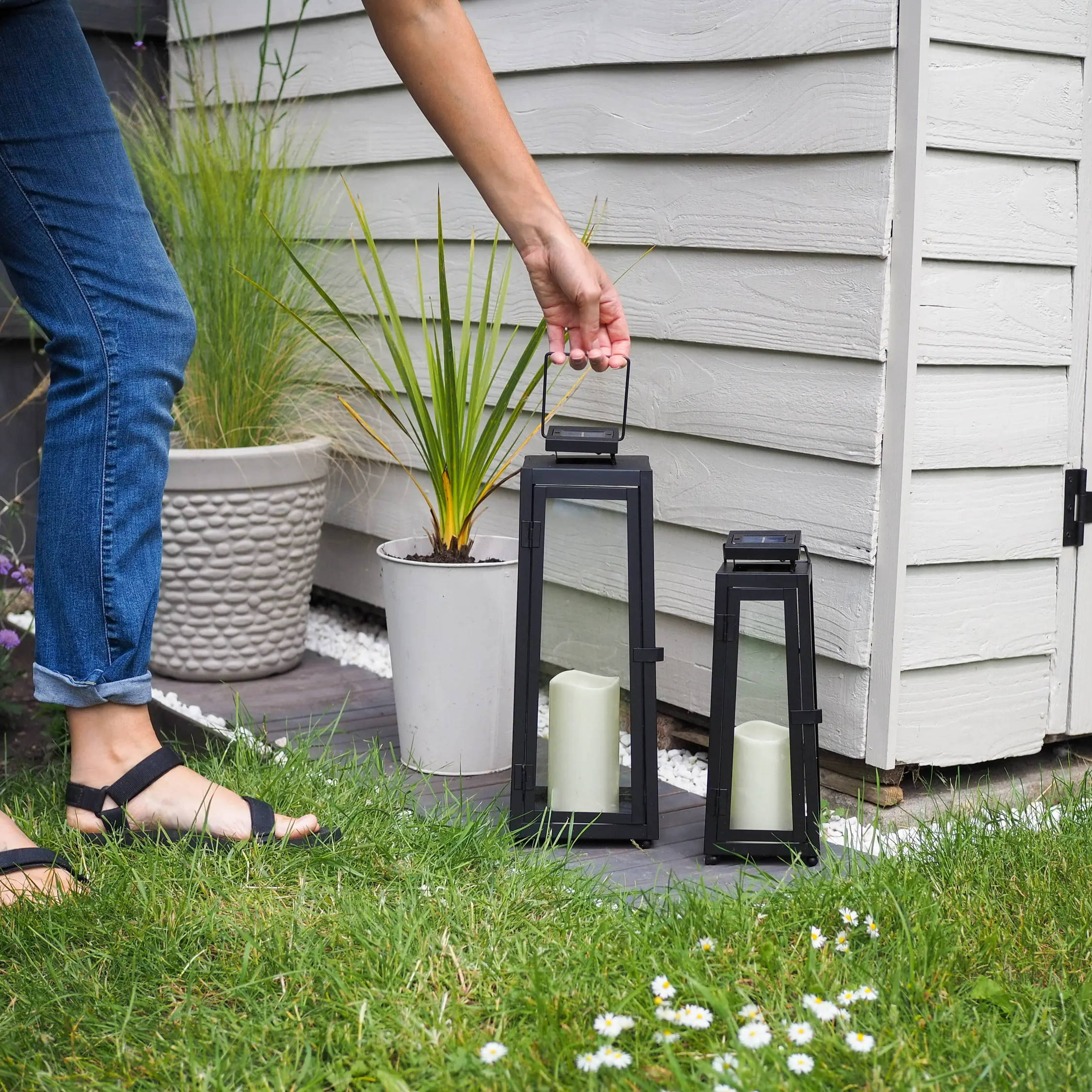 Person placing 2 solar lanterns on the floor next to her garden shed.