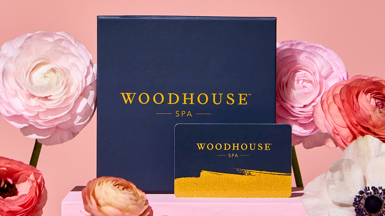 Woodhouse Spa Mother’s Day gift card and navy gift box styled with soft pink florals on a blush background.