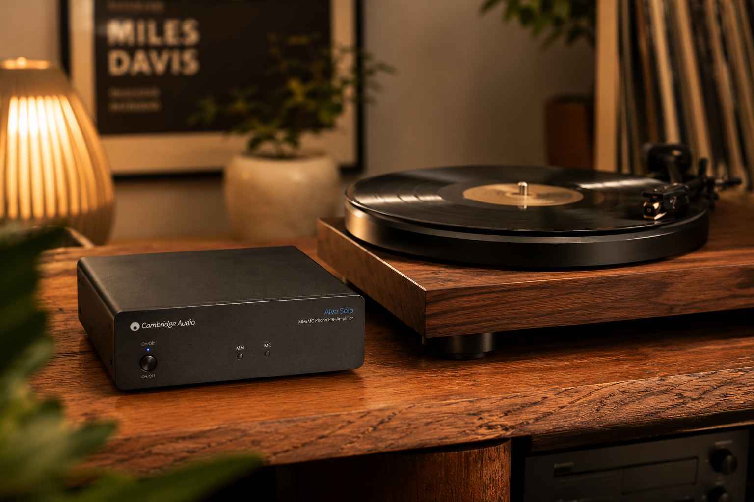 Turntable and speaker on a wooden table with a lamp in the background.