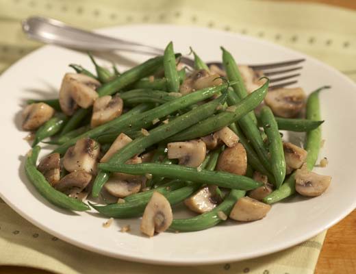 A plate of sautéed green beans and mushrooms.