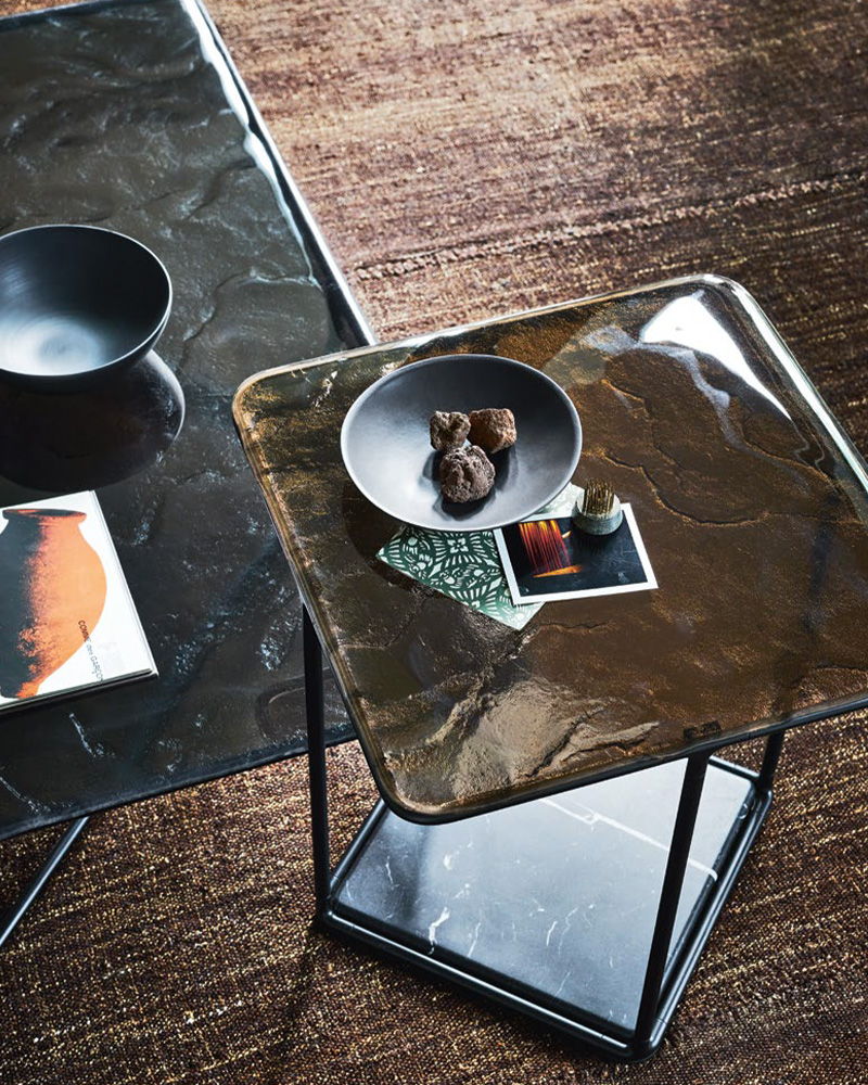 Two modern B&B italia side tables with black bowls and decorative items on top.