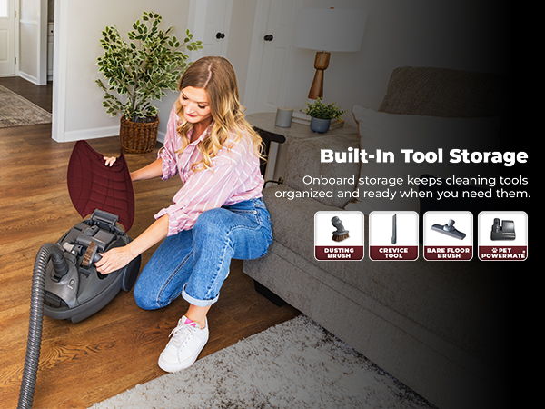 Woman cleaning with vacuum, showcasing built-in tool storage features.