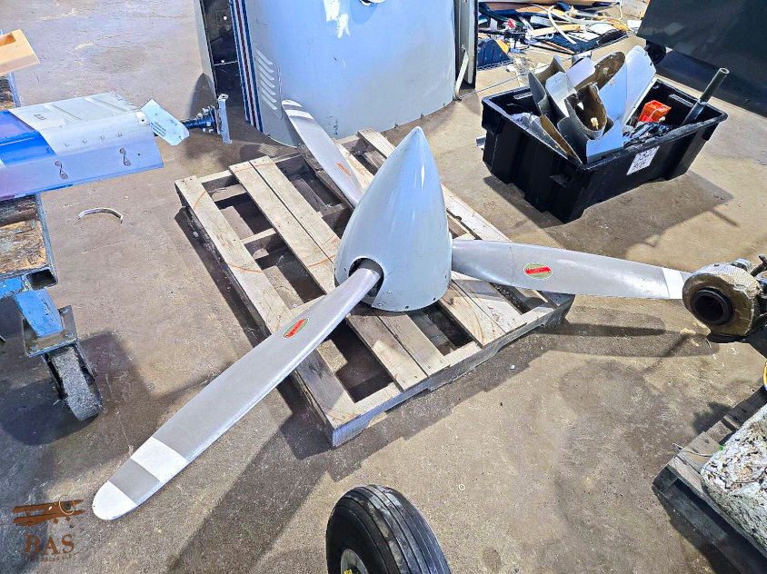 Aircraft propeller on a wooden pallet in a workshop setting.