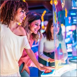 Two women enjoying a game in a colorful arcade setting.