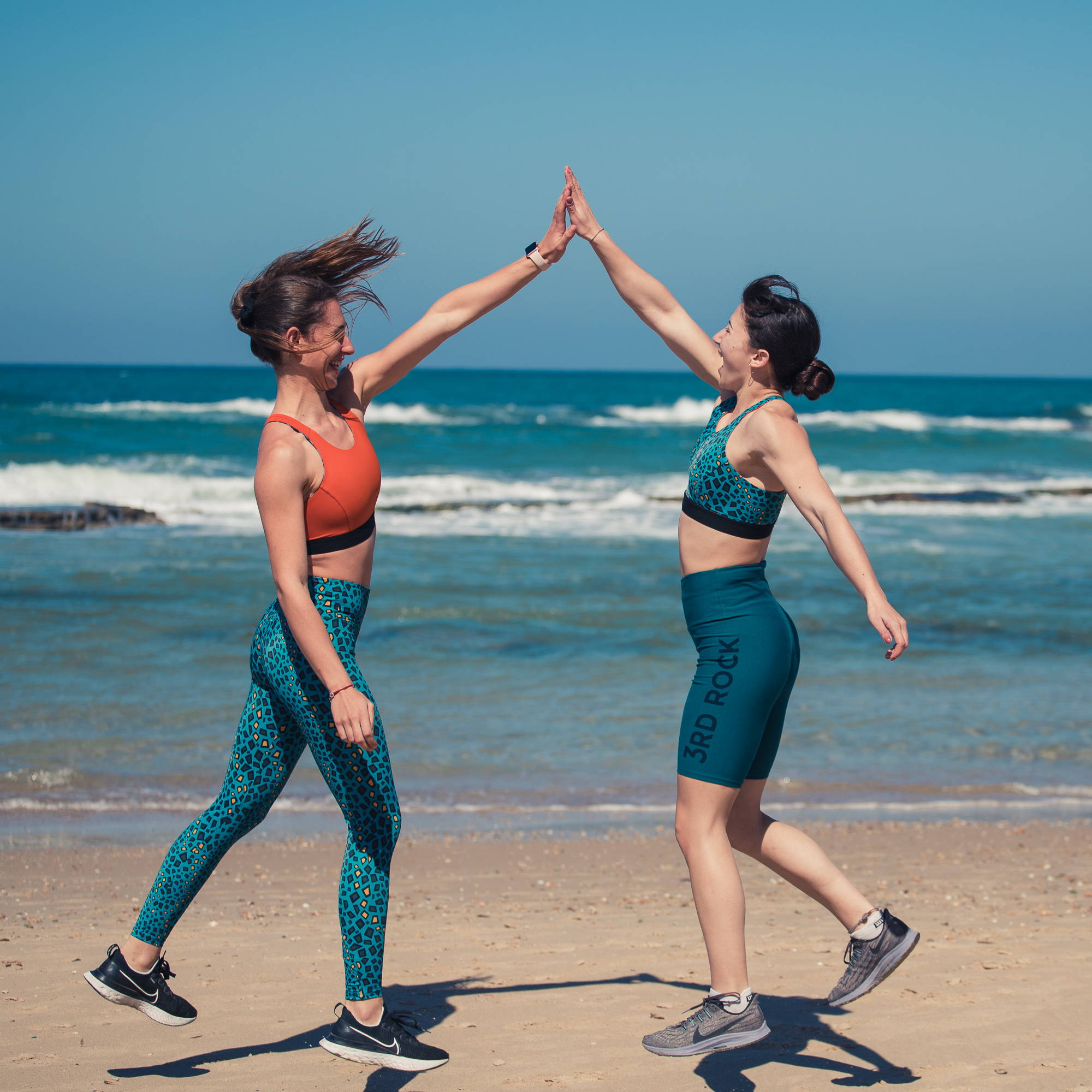 A shot from one of our Summer shoots on the beach. This photo features two of our models sharing a solid high five with the ocean in the background.