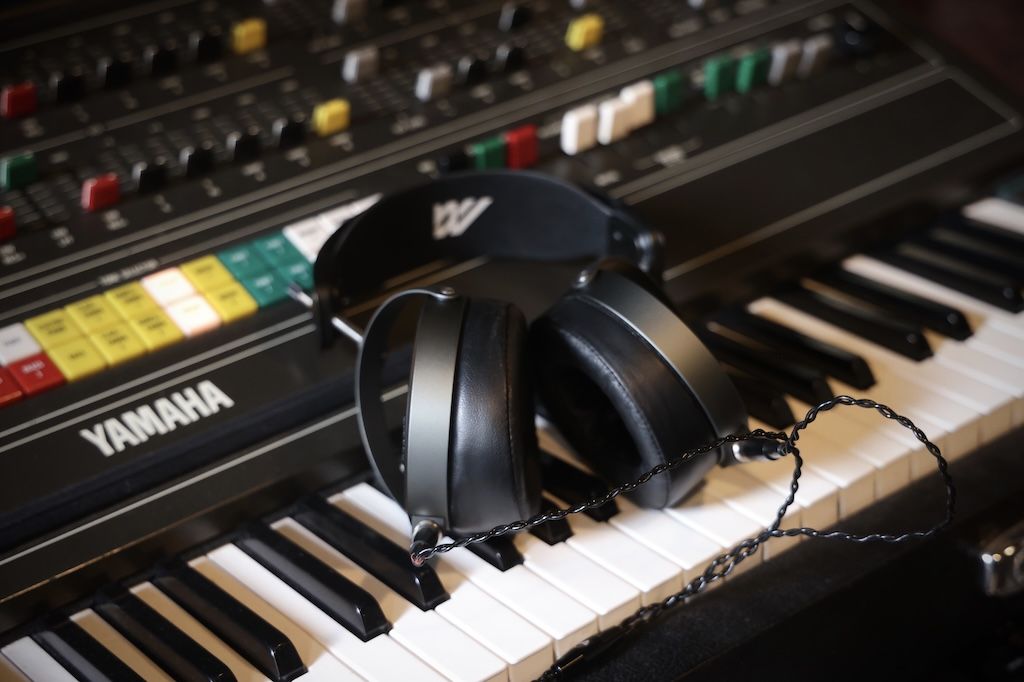 Black headphones resting on a piano keyboard beside a Yamaha synthesizer.