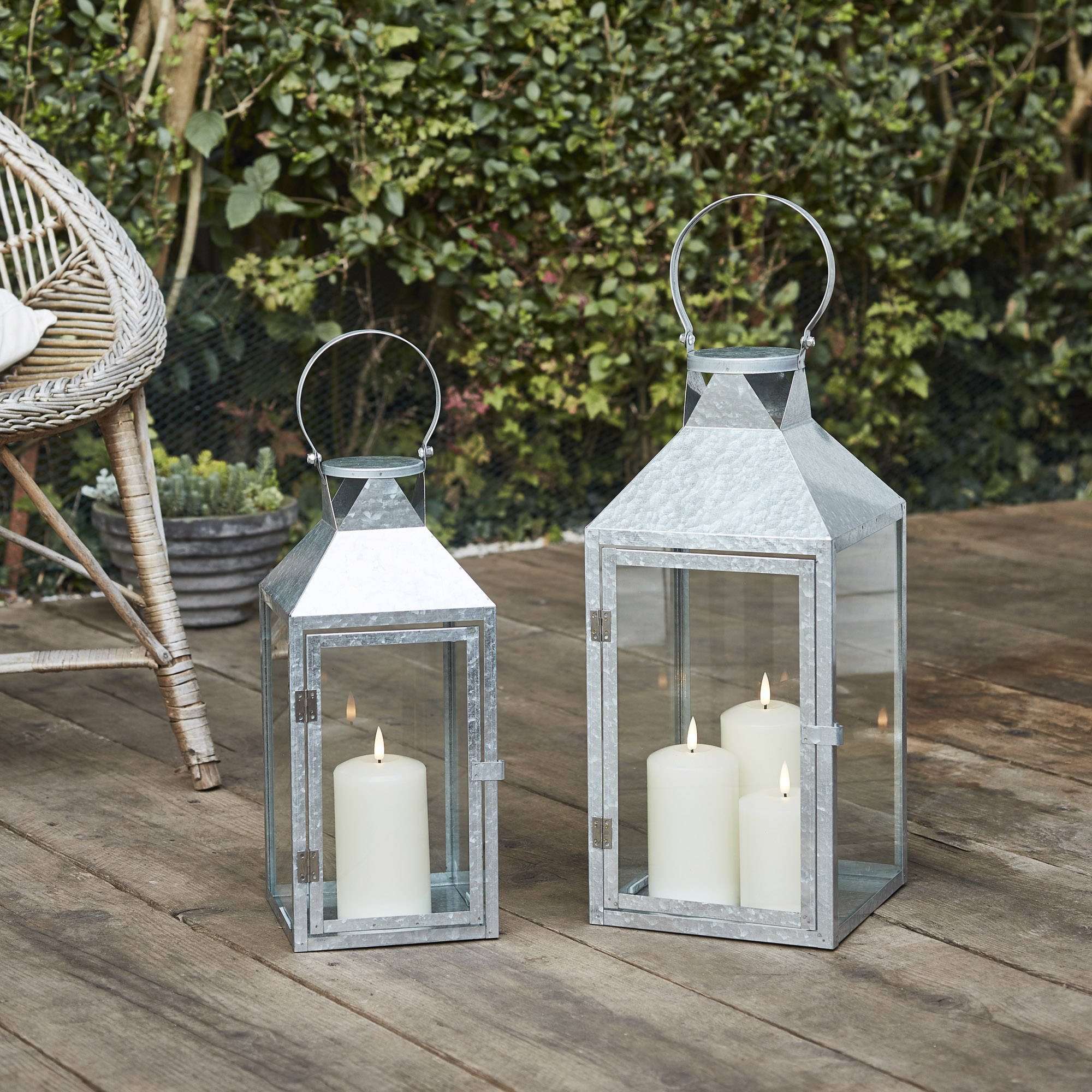 Two metal lanterns with LED candles on a garden decking