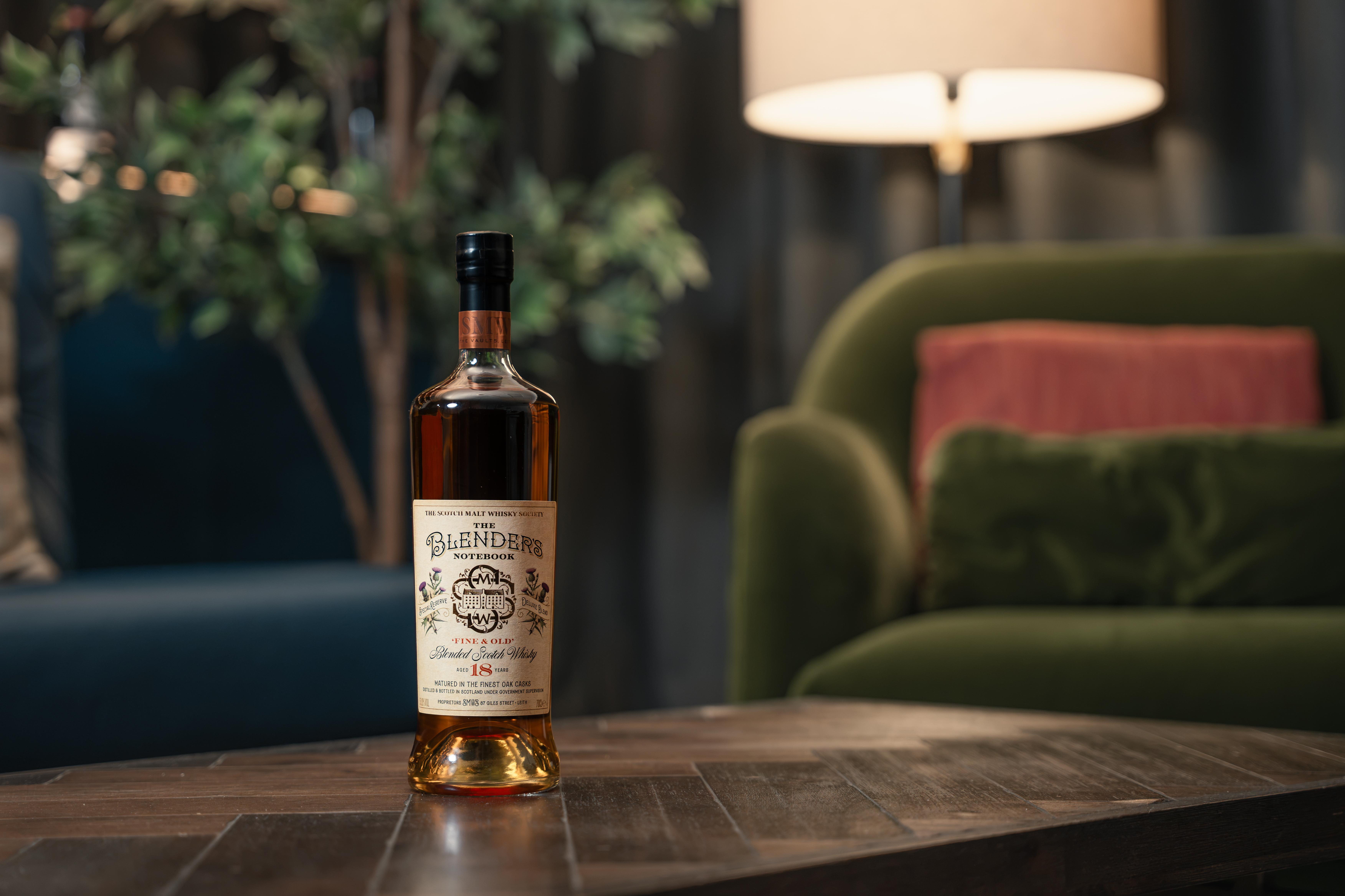 A bottle of whiskey on a wooden table in a cozy living room.