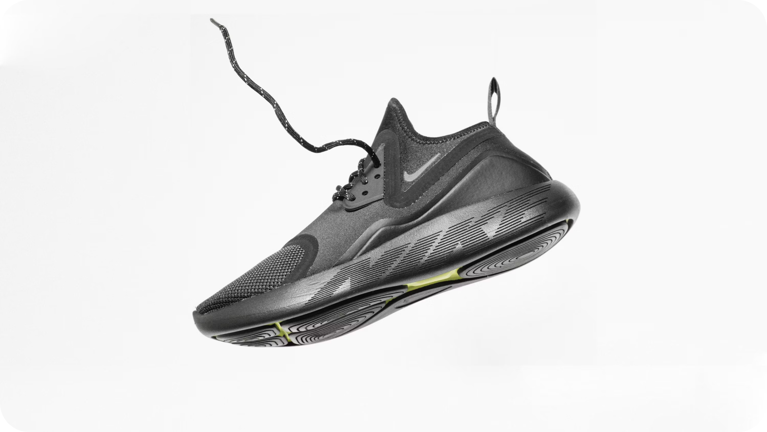 A black sneaker on a white background, being dropped from above.