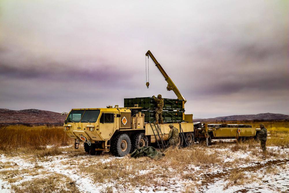 Ammunition Crew picking up the Ammunition for the Multiple Launching Rocket System (MLRS) on a Heavy Expanded Mobility Tactical Truck (HEMTT).