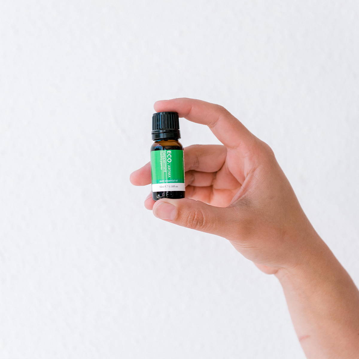 Hand holding peppermint essential oil