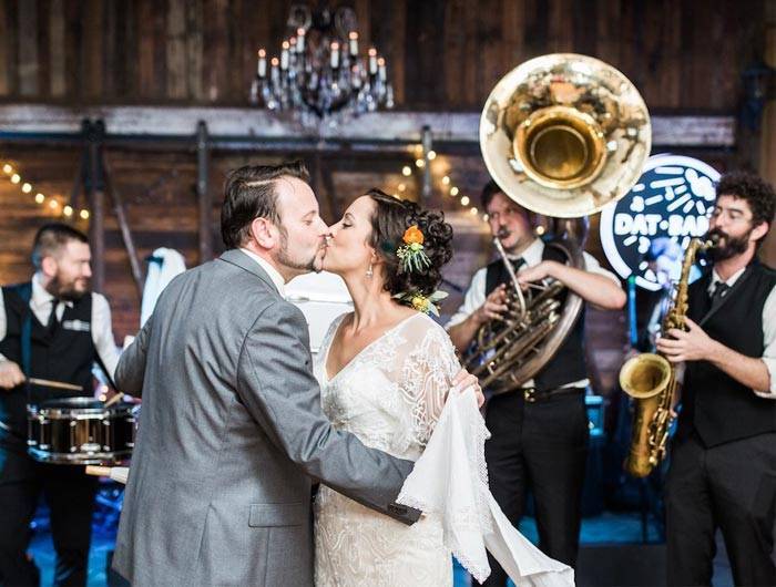 Bride and groom kissing in front of band at wedding reception