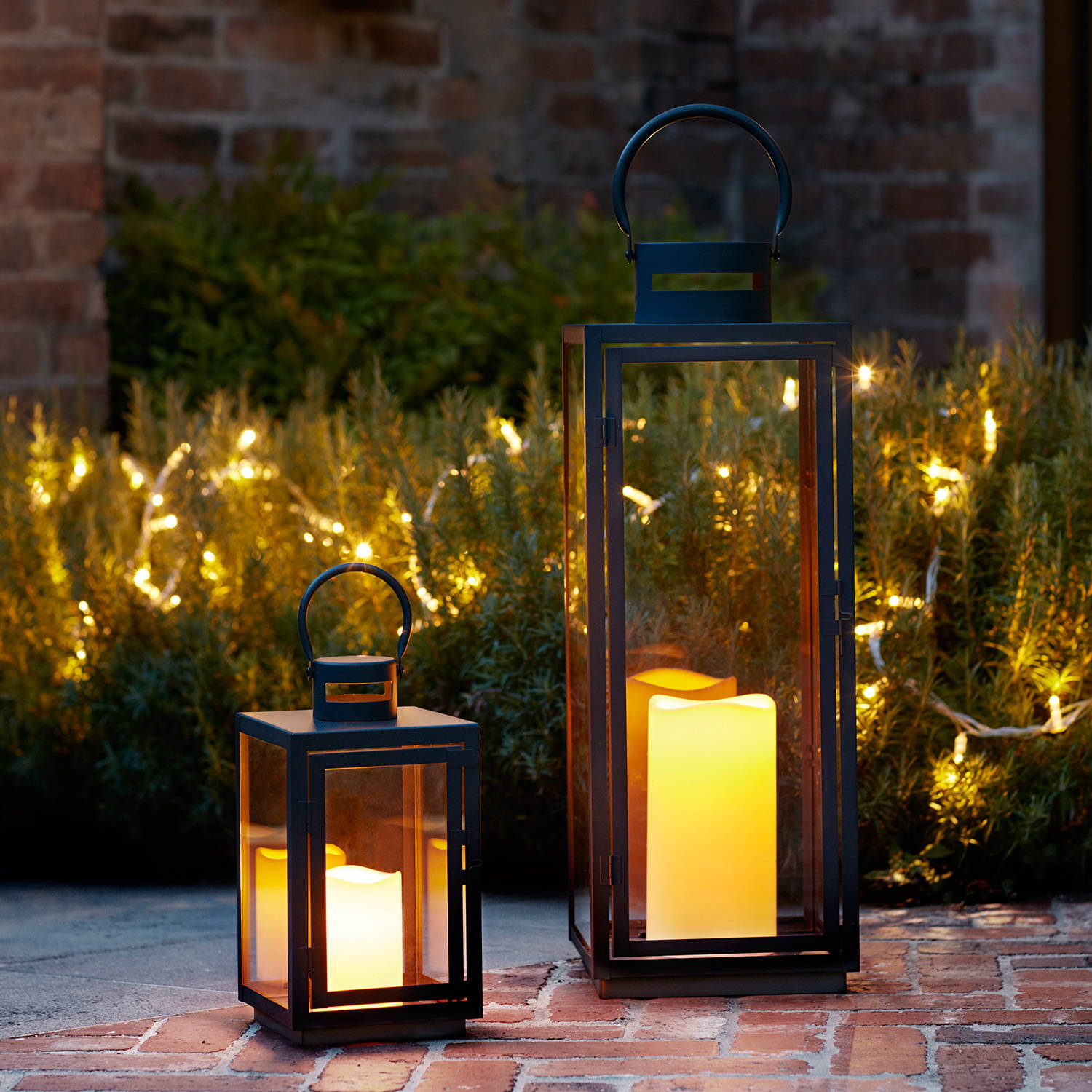 Outdoor lanterns and candles on a patio with fairy lights