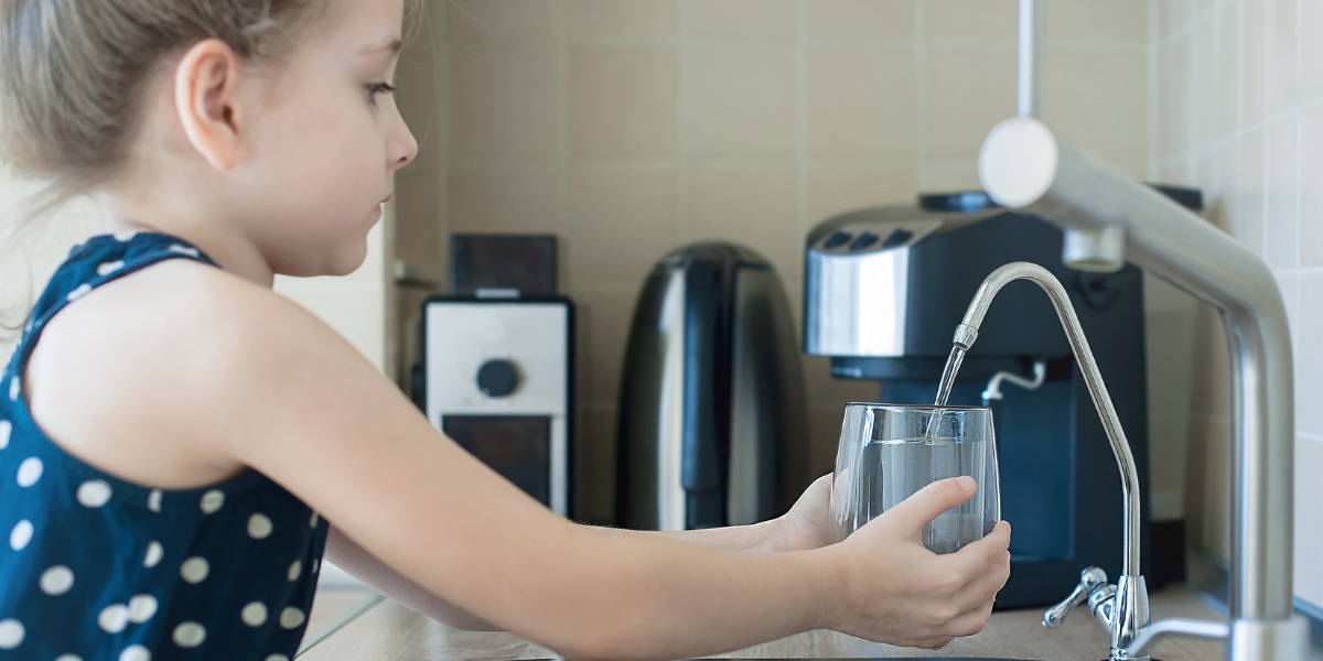 Barn fyller koppen med filtrert vann