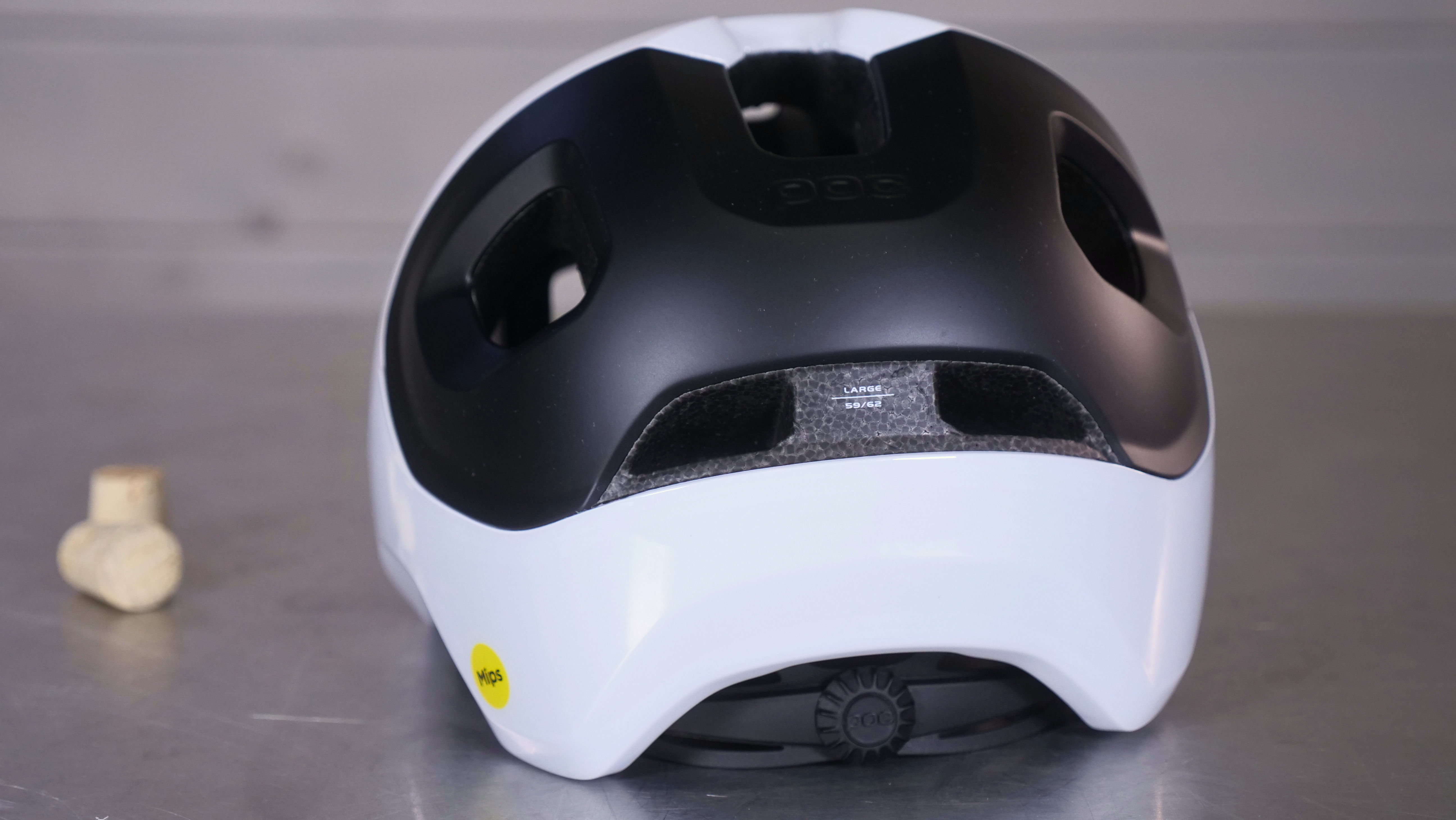 A black and white helmet viewed from the back on a gray surface.