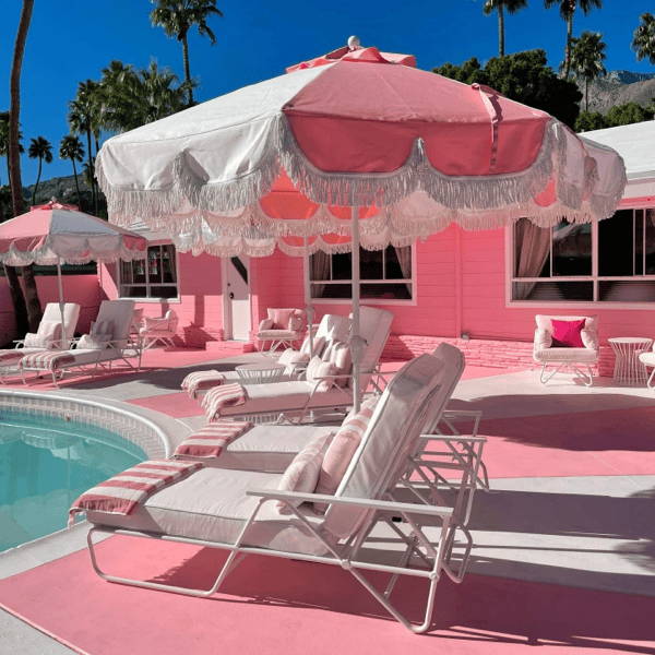 Pink and white pool side umbrella with tassels. 