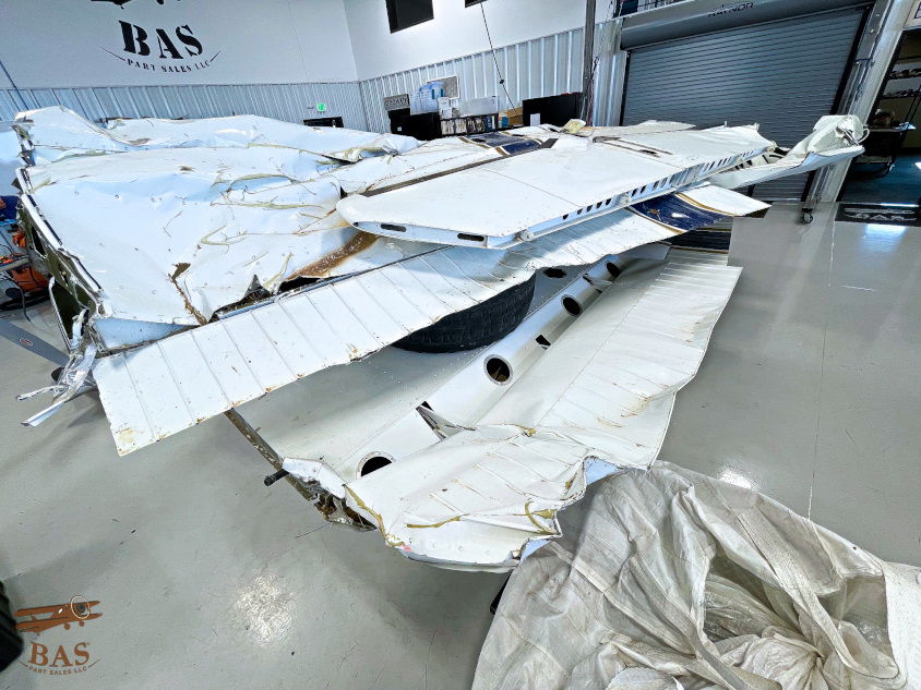 Damaged aircraft parts in a hangar, with debris on the floor.