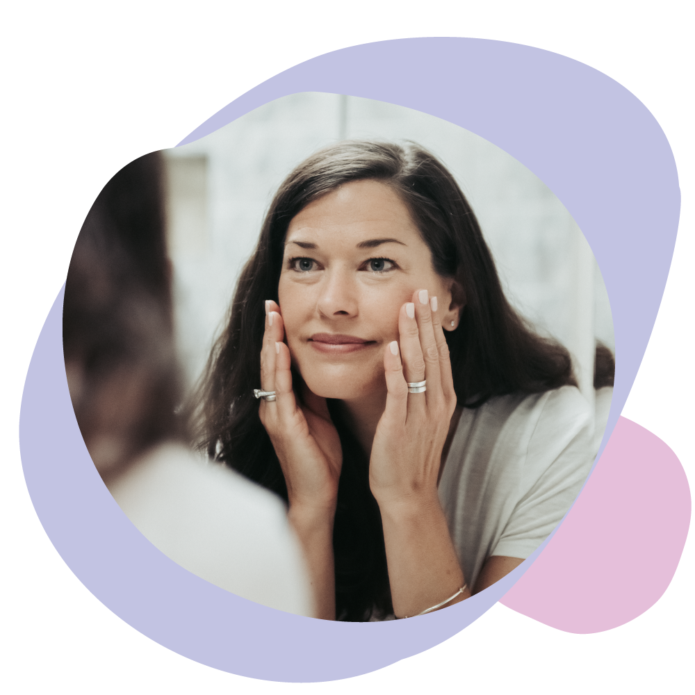 Woman looking in mirror applying hydrating night cream to face