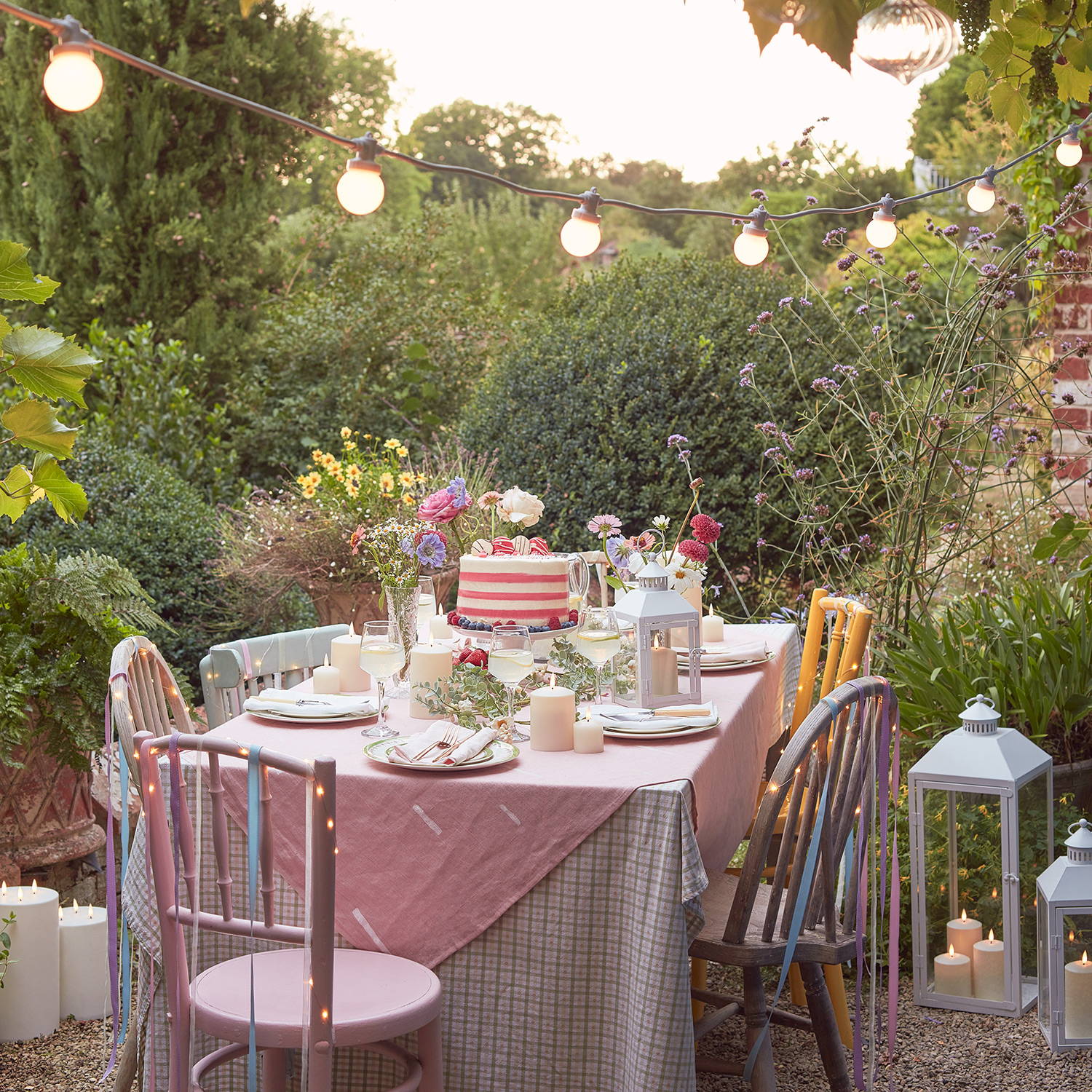 Une table d'extérieur avec une guirlande guinguette pro connect suspendue en hauteur. 