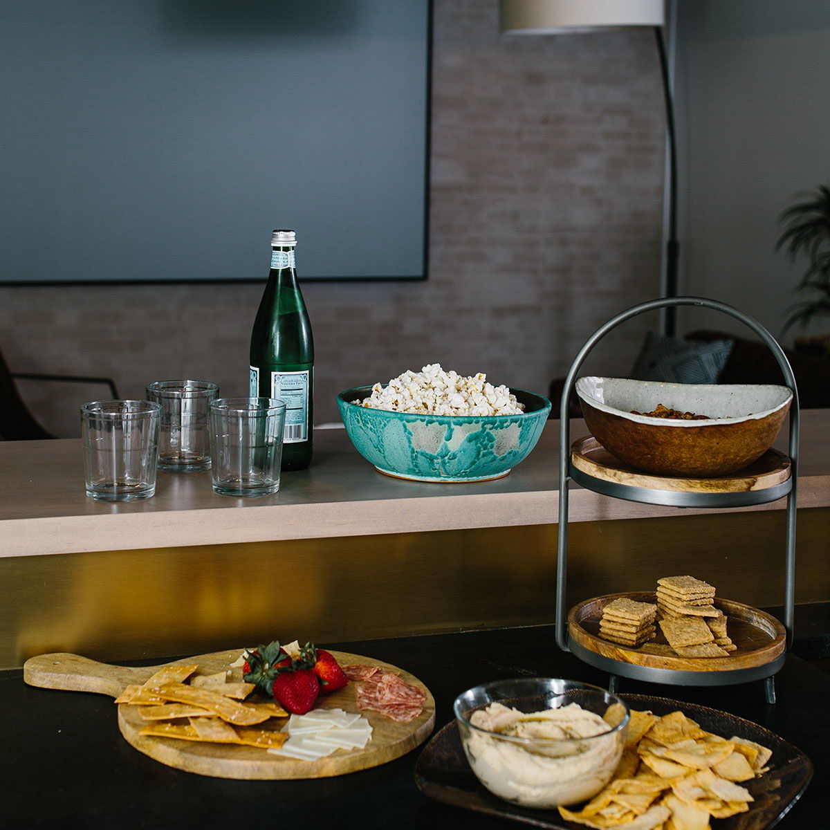 A spread of snacks and drinks on bar in tv room.