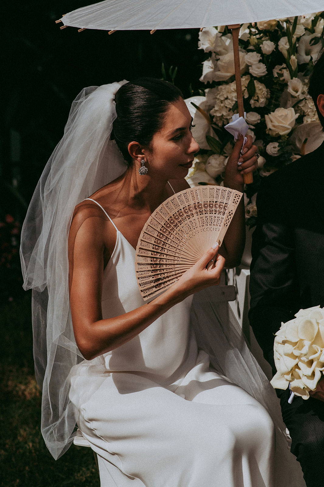 La mariée s'évente avec un éventail en bois.