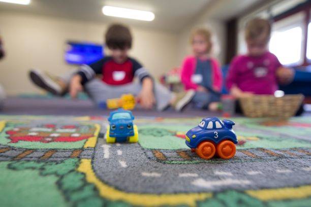 Children At Nursery With Car Toys On The Carpet