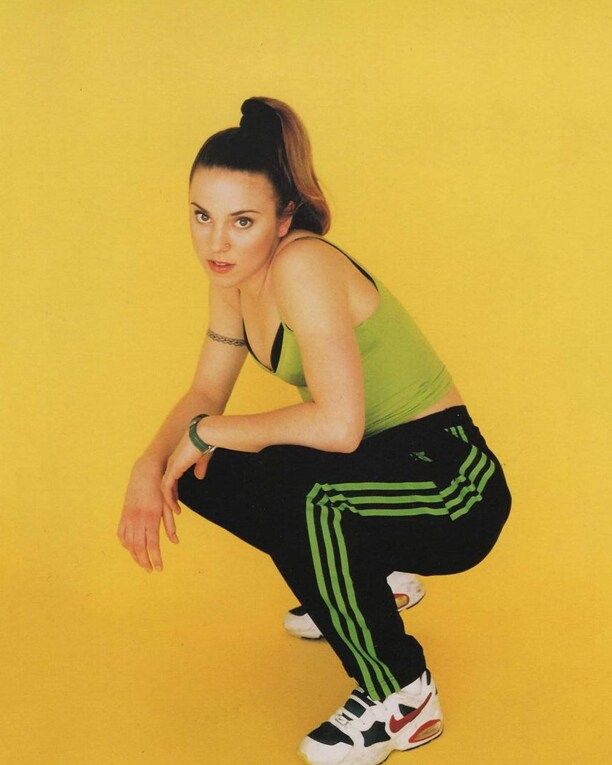 Person in athletic wear squatting against a bright yellow background.