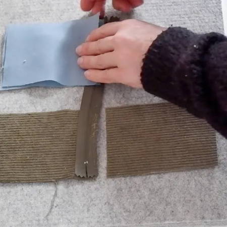 hands folding the fabric on the zipper to sew them together correctly