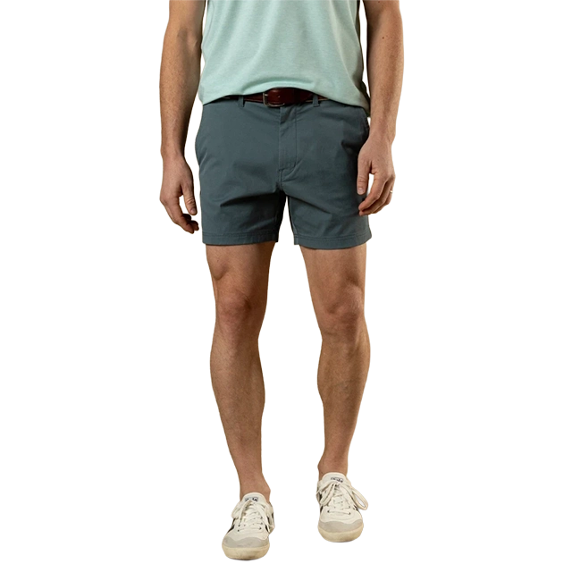 A man wearing a light shirt and shorts, standing with feet together.