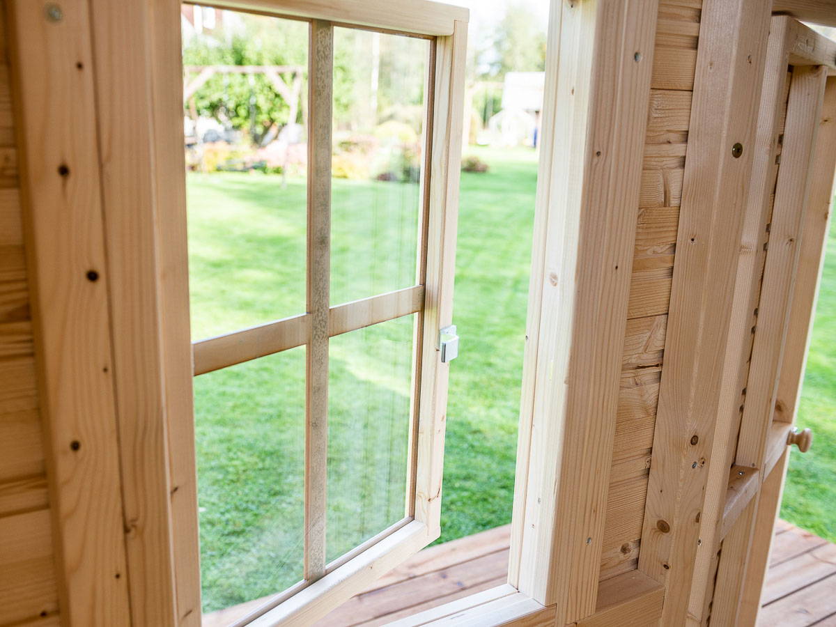 Wooden Playhouse window opened from the inside looking onto green grass by WholeWoodPlayhouses