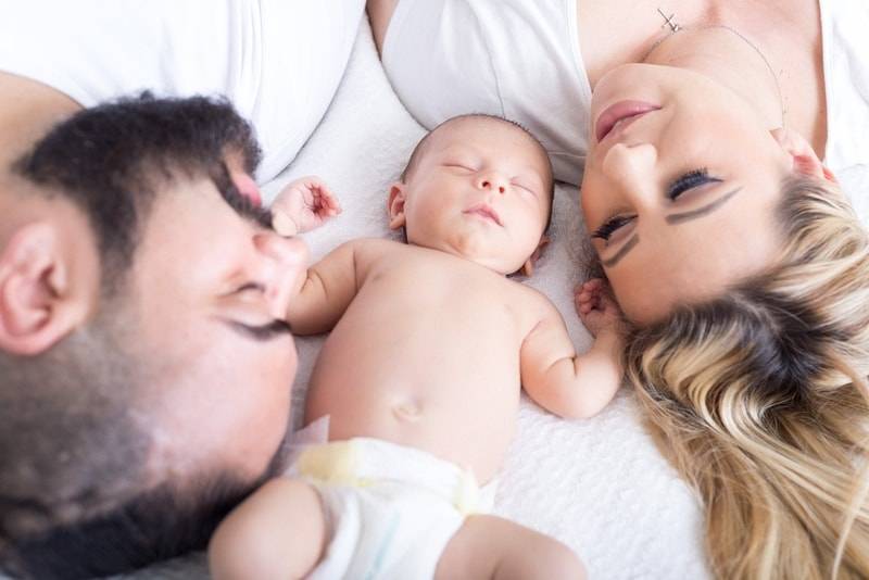 parents lying down with baby asleep