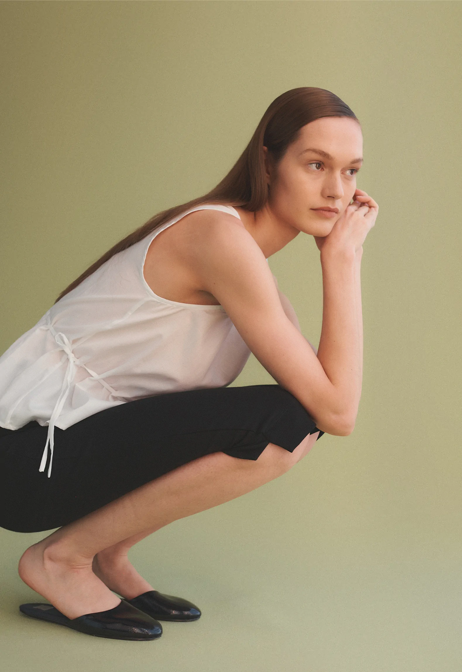 woman crouched down with elbows on knees and hands clasped on cheek