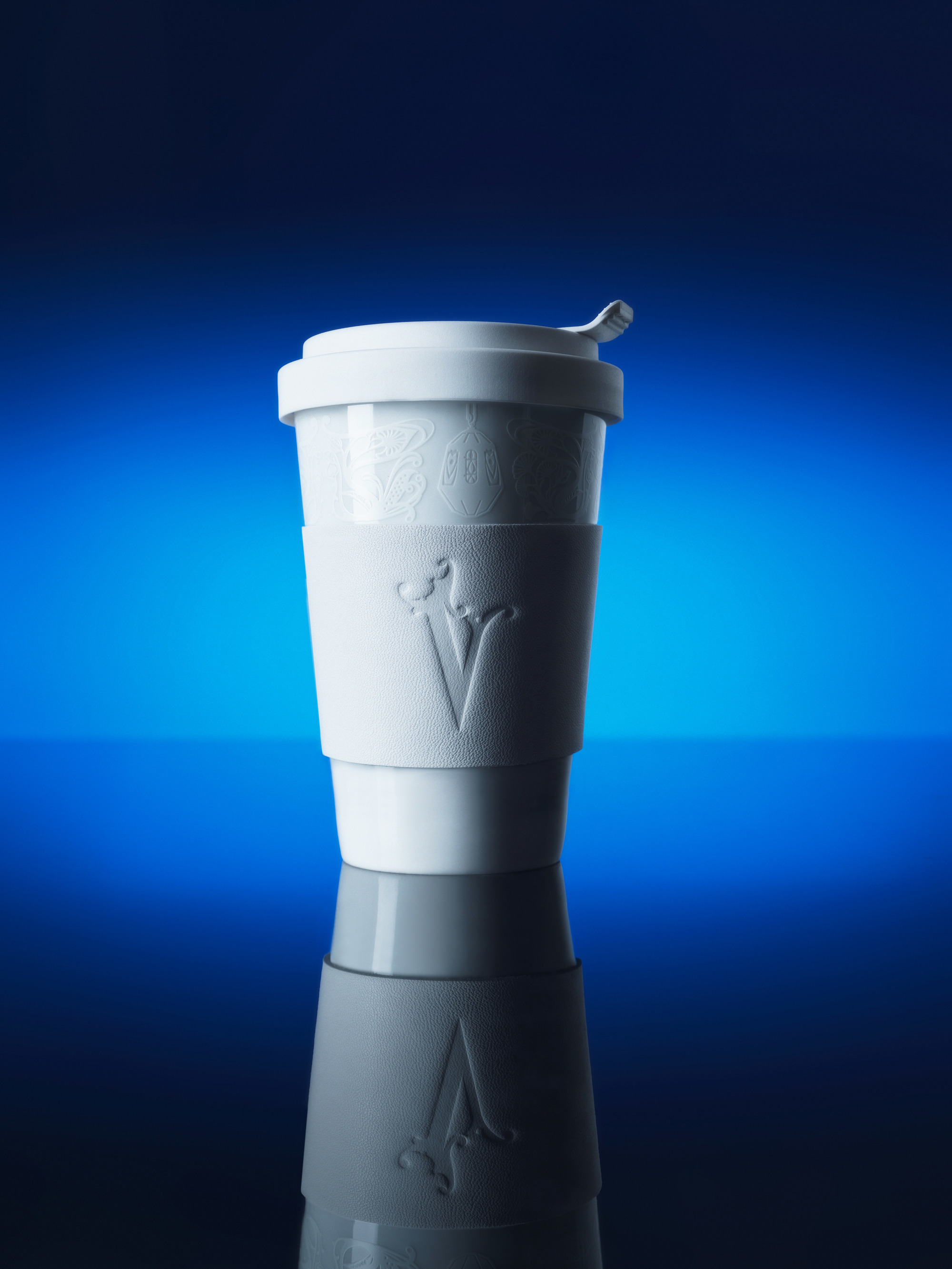 White coffee cup on a reflective surface with a blue background.