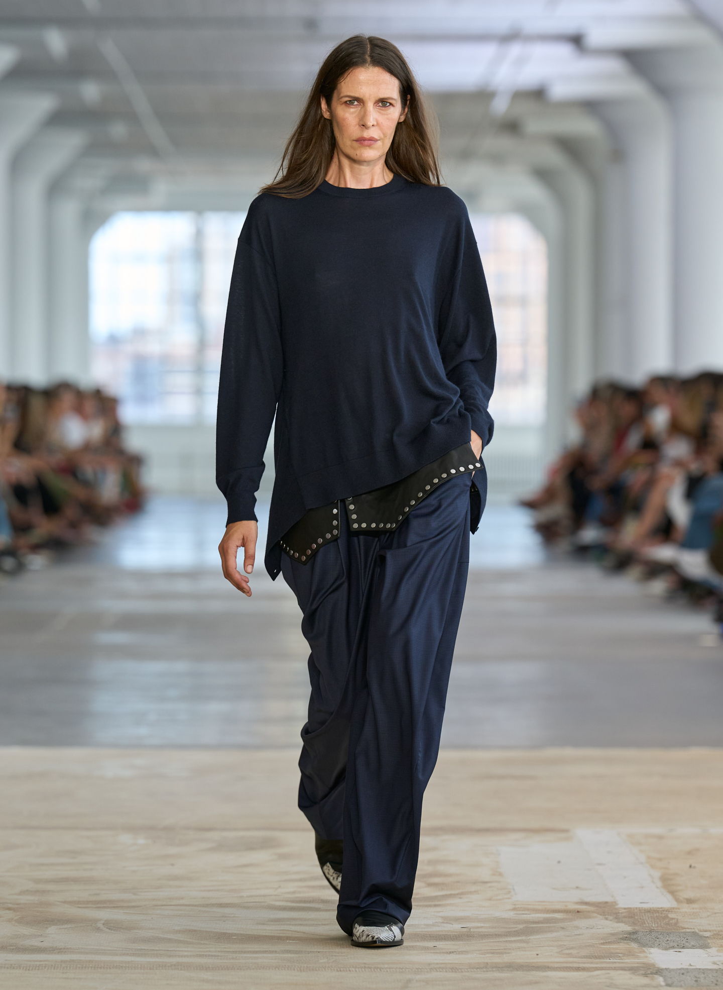 Model walking the runway in casual navy outfit during a fashion show.