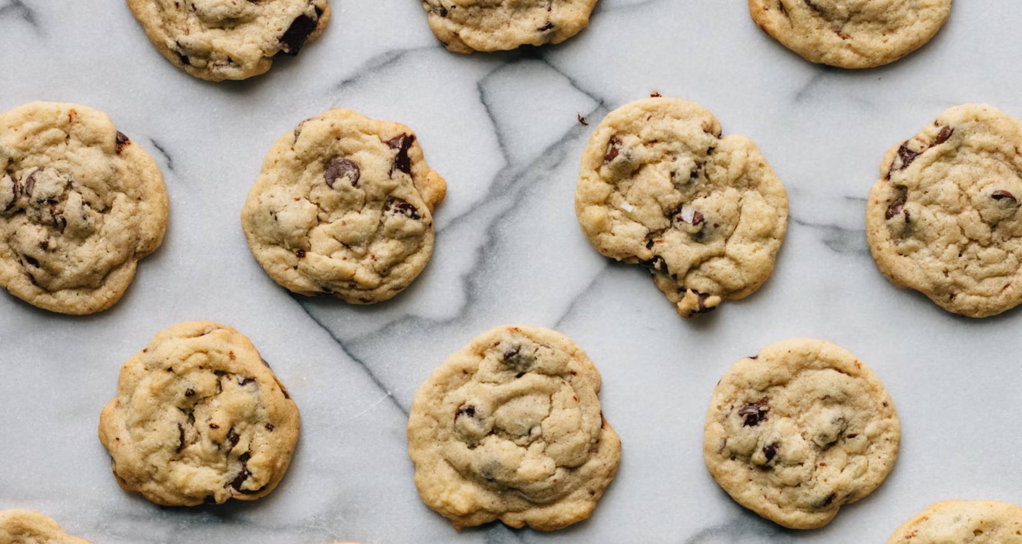 rows of chocolate chip cookies on a marble countertop
